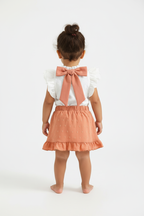 Petite fille en ensemble blanc et rose corail - vue de dos