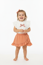 Petite fille en ensemble blanc et rose corail - vue de face