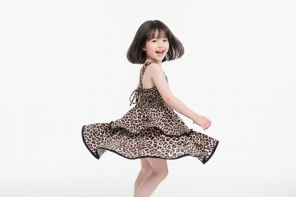 Petite fille qui virevolte dans la robe léopard avec dos nu lacé et jupe à volants