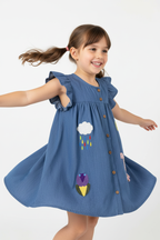  "Fillette 4-6 ans virevoltant et tournant sur elle-même - Robe denim bleu avec appliqués colorés ludiques - Vue trois-quarts angle diagonal montrant mouvement de la robe trapèze évasée - Tenue casual chic - Fond blanc studio professionnel - Photo produit lifestyle action BabyCoton Suisse - Style décontracté ludique petite fille"