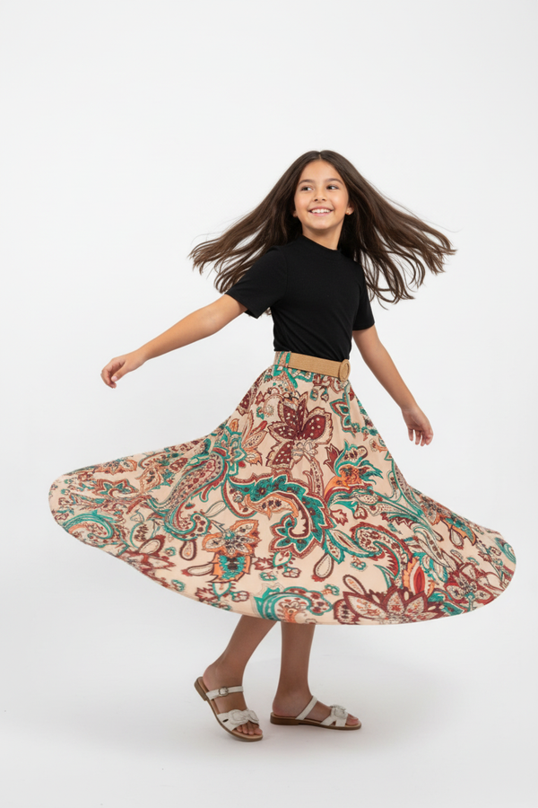 "Fillette 6-8 ans virevoltant et tournant sur elle-même - Robe haut noir et jupe paisley avec ceinture - Vue trois-quarts angle diagonal montrant mouvement de la jupe longue qui virevolte - Tenue élégante chic - Fond blanc studio professionnel - Photo produit lifestyle action BabyCoton Suisse - Style raffiné petite fille"