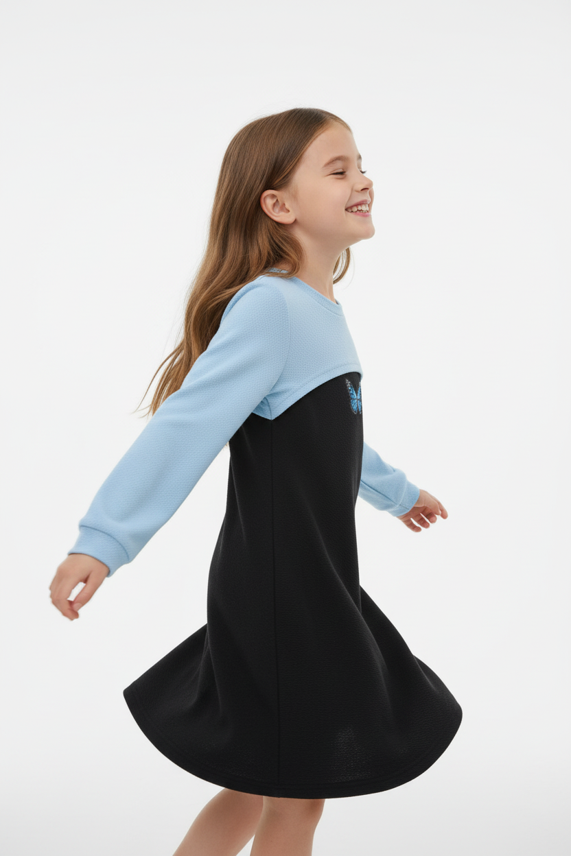 Fillette en mouvement portant robe bicolore bleu et noir motif papillon - Vue de côté