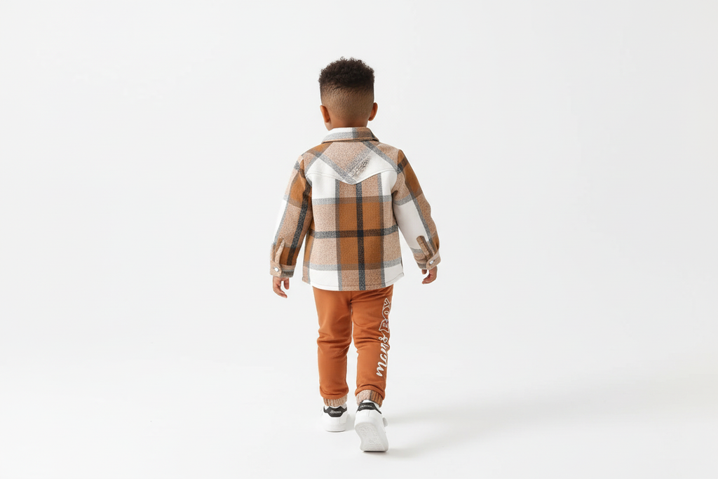 Vue arrière d'un garçon d'origine diverse portant une chemise boutonnée à carreaux beige et blanc avec pantalon orange

