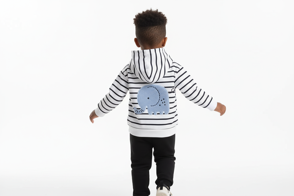 Vue arrière d'un enfant d'origine diverse portant un hoodie blanc à rayures noires avec appliqué éléphant bleu et pantalon noir
