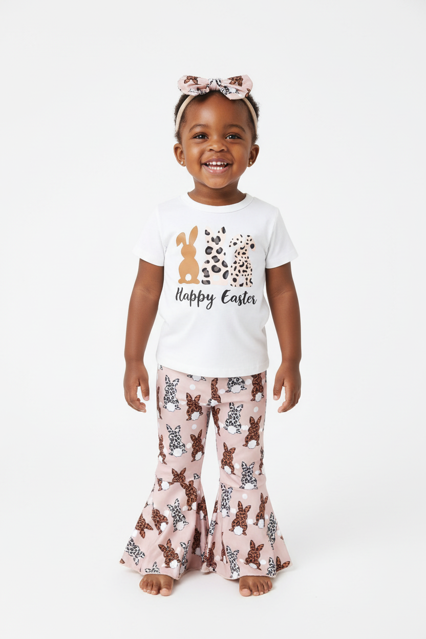 	Fillette debout en ensemble Happy Easter BabyCoton — t-shirt blanc lapins léopard, pantalon évasé rose lapins et bandeau nœud léopard, fond blanc