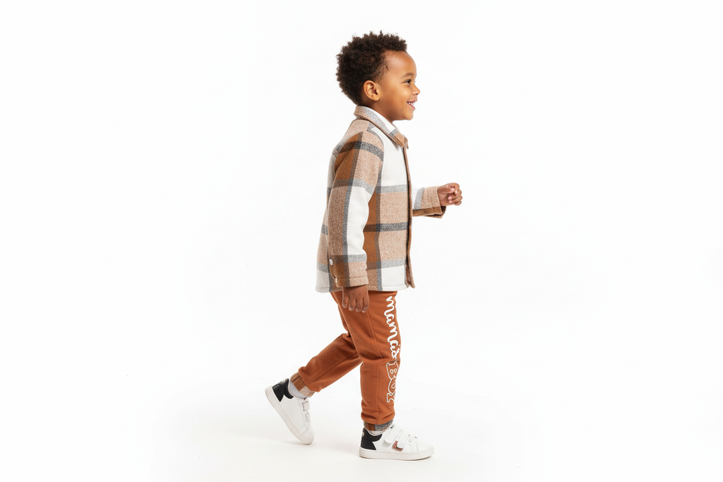 Vue de profil d'un garçon d'origine diverse portant une chemise boutonnée à carreaux beige et blanc avec pantalon orange
