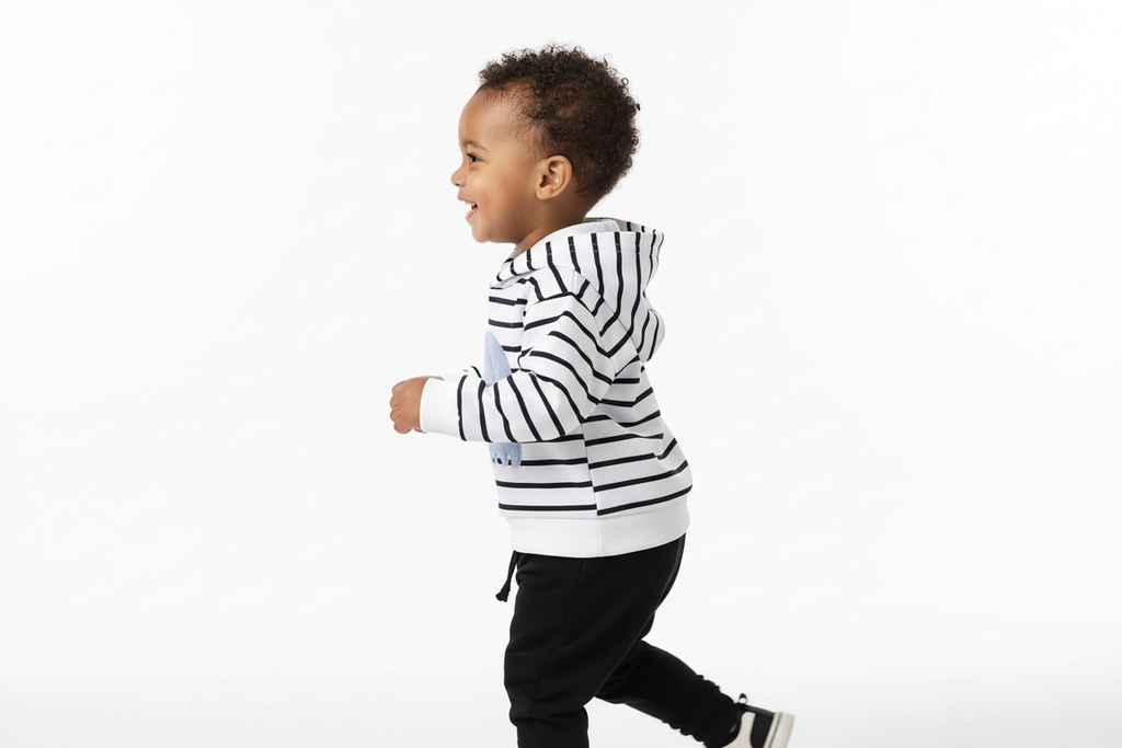 Vue de profil d'un enfant portant un hoodie blanc à rayures noires avec appliqué éléphant bleu et pantalon noir
