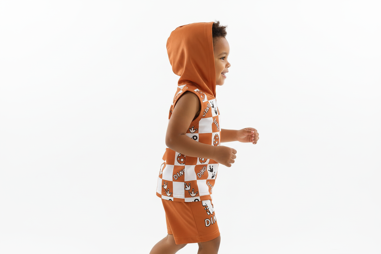 Vue de profil d'un enfant portant un débardeur à capuche orange à carreaux avec motifs dinosaures DINO et short orange assorti
